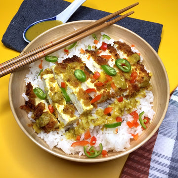 Crispy Curried Katsu Bowl:Colorful warmly spiced aromatic bowl of goodness. Japanese style crispy golden panko breaded tofu with rich, creamy, fruity curry sauce, carrots and peas served over bowl of hot fluffy rice.
