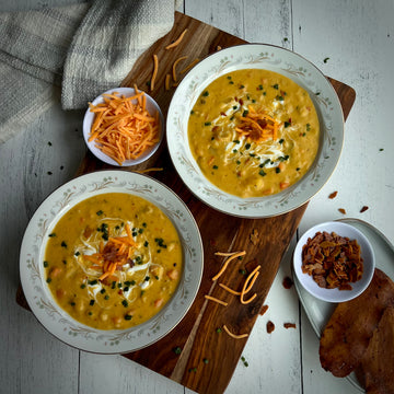 Loaded Potato Soup; A rich, creamy, cheesy soup version of loaded potato is a pure comfort in a bowl. Loaded with tender potatoes, carrots, and chickpeas in a thick creamy broth, topped with plant based smoky bacon pieces and shredded cheese.